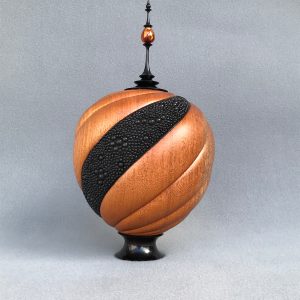 Spiral-carved and embellished hollow vessel with finial.