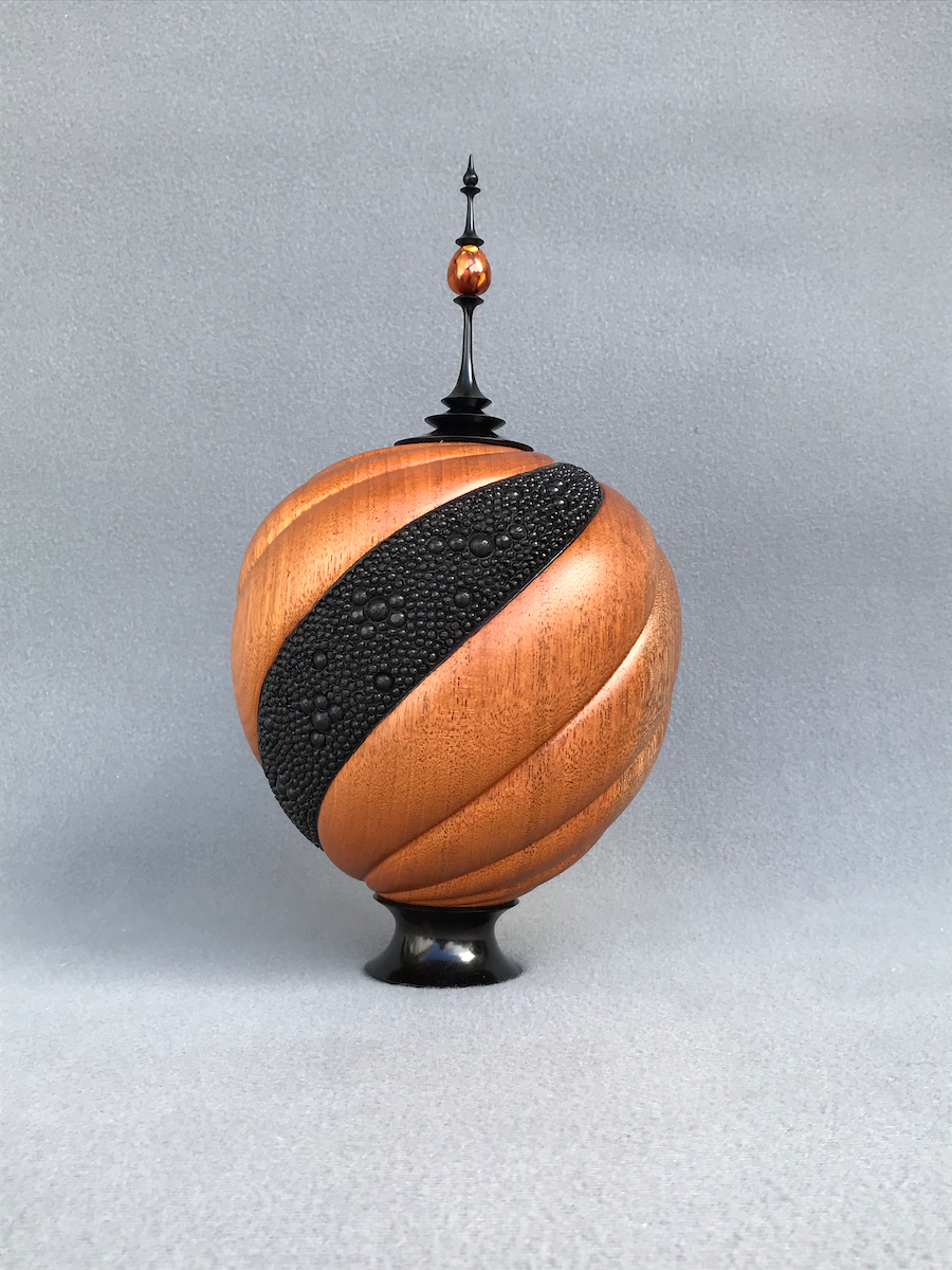 Spiral-carved and embellished hollow vessel with finial.
