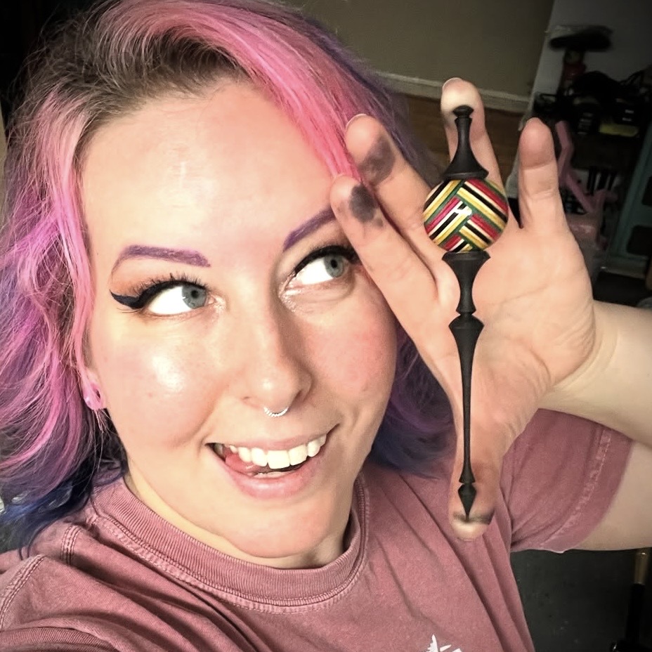 Closeup of smiling Ms. DeGroot holding her turned ornament up close to her face.